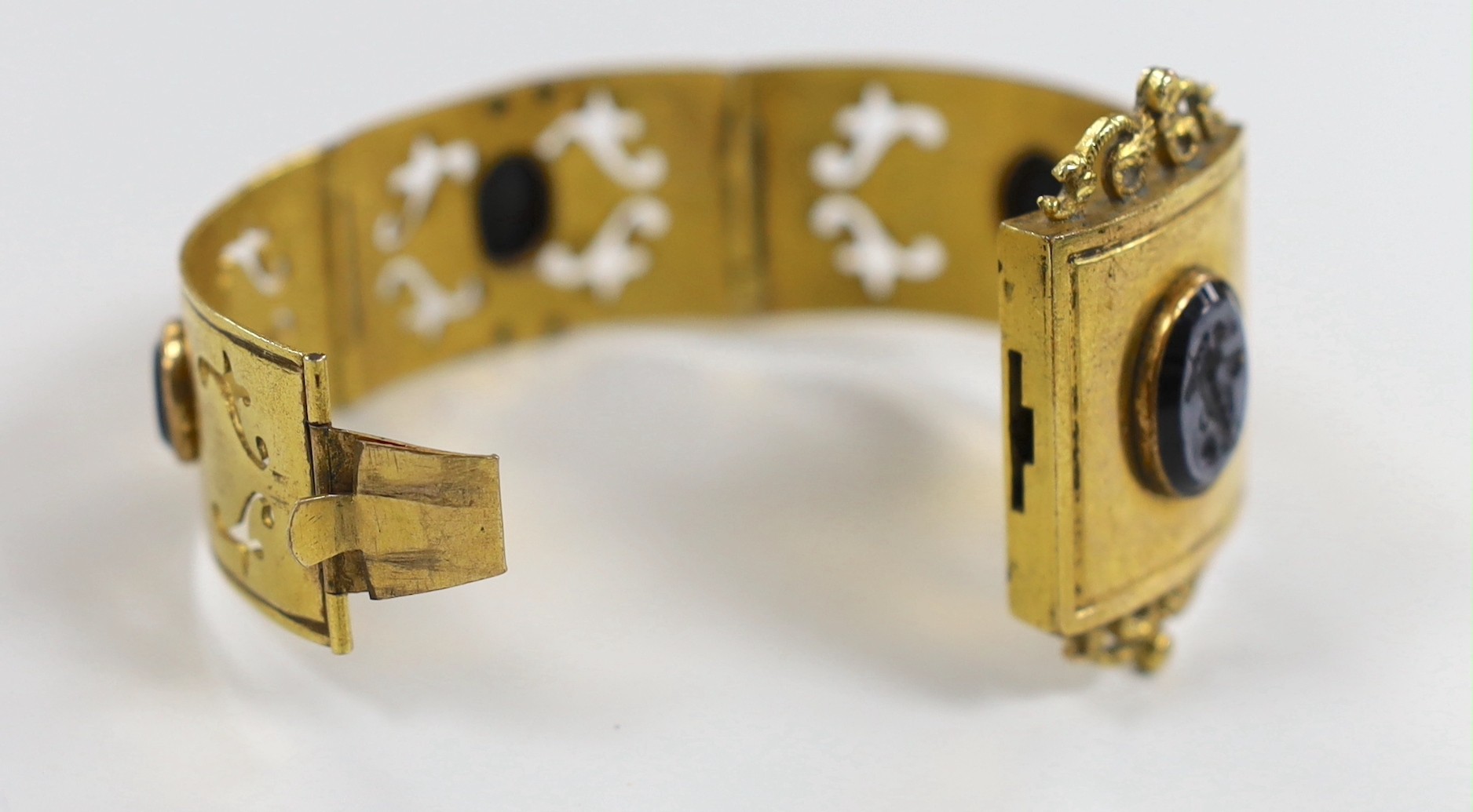 A Victorian gilt metal and four stone glass intaglio set bracelet, (repair), each stone carved with a cherub, 15cm.